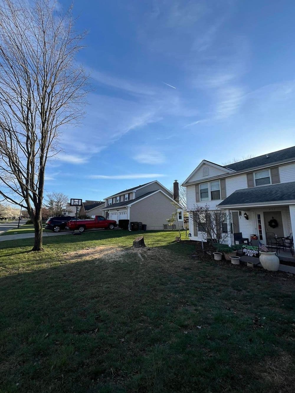 Residential property with a red truck, blue sky, and two houses side by side.