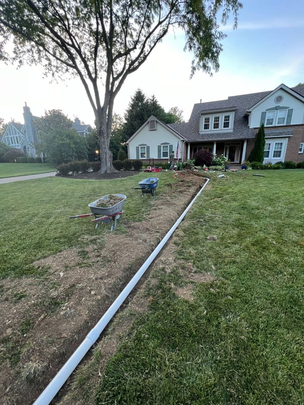 Landscaping project with tools and a trench for drainage at a residential home.