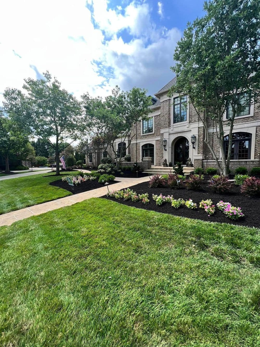 Elegant brick home with landscaped garden, flower beds, and a welcoming pathway.