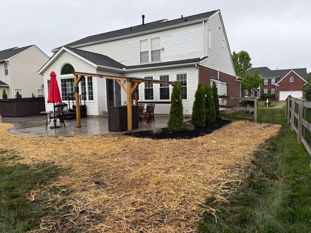 Backyard view of a home with patio, outdoor seating, and freshly mulched landscaping.