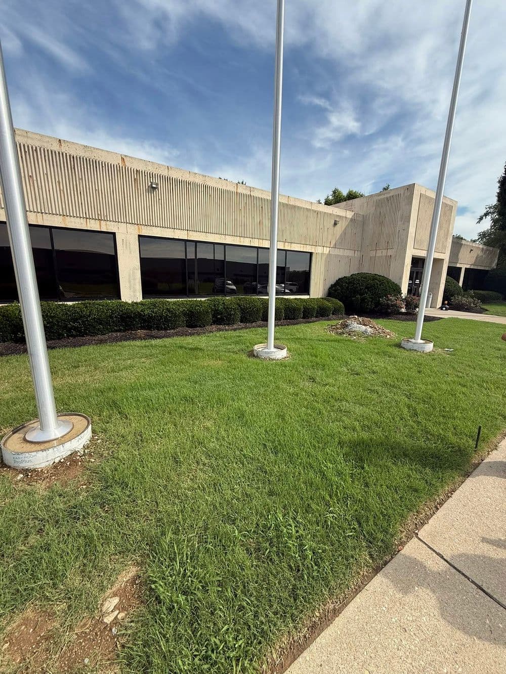 Building exterior with large windows, well-maintained lawn, and flagpoles in foreground.